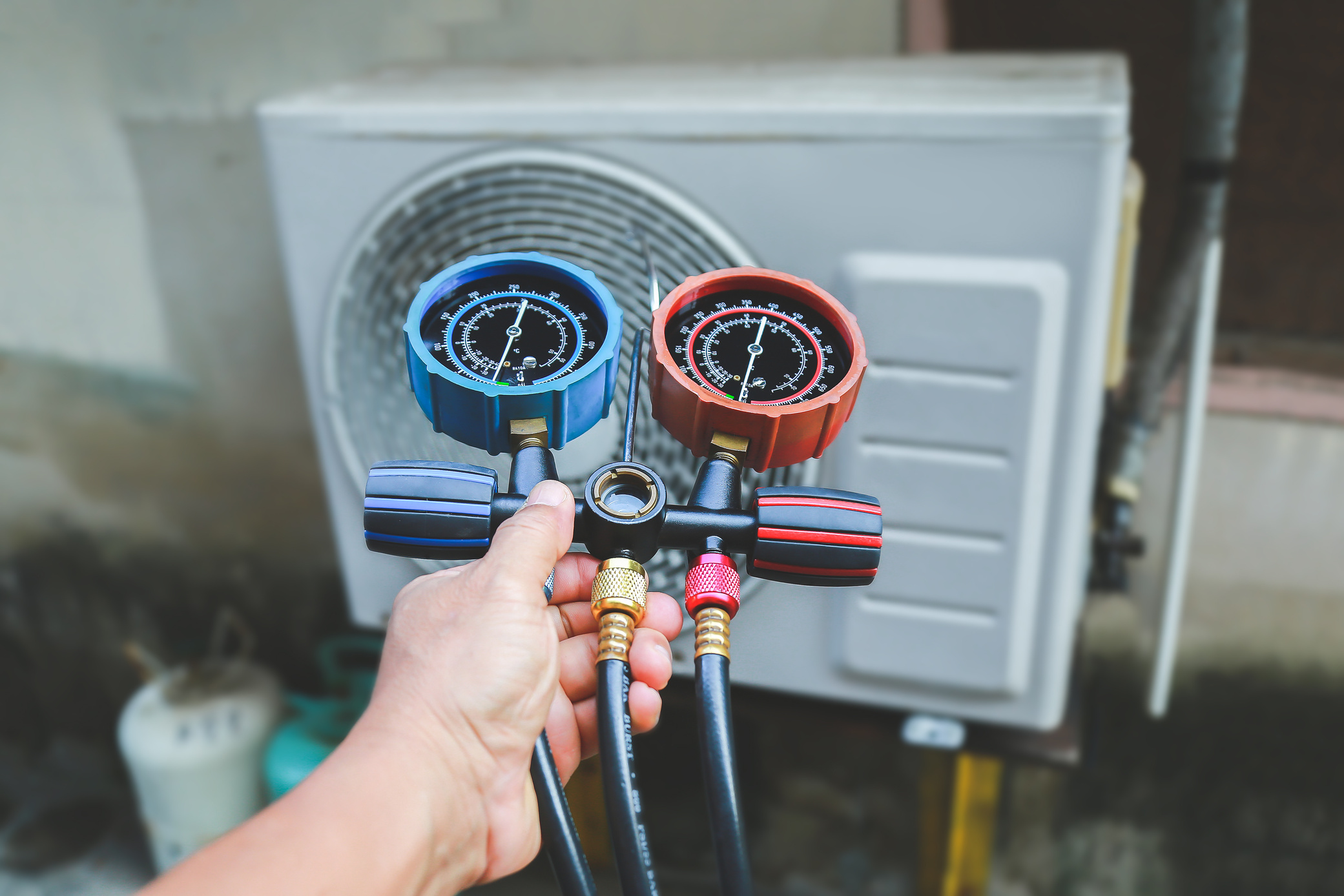 Air conditioning, HVAC service technician using gauges to check refrigerant and add refrigerant.